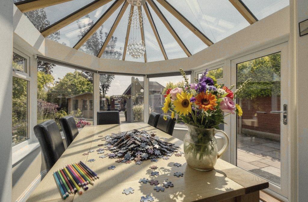 A conservatory table with a half-finished jigsaw, colouring pencils and garden flowers